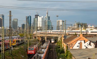 Frankfurt Almanya tren ve silueti - 19 Temmuz 2023 ICE ve kargo treni Frankfurt 'tan ayrılıyor. Sinyal sistemleri, demiryolu bağlantıları ve şalterleri. Arkaplanda binalar, gökdelenler.