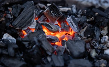 Mangal ızgarasında kömür közleri. Ateşe yakın çekim, parlayan kömür ve sıcak közler. Yaz, sıcak, sıcaklık, boş zaman aktivitesi, açık hava, barbekü sezonu.