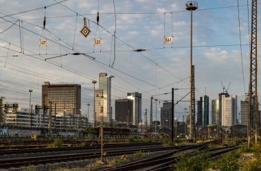 Demiryolu rayları, tren ve ufuk çizgisi. Frankfurt Almanya - 19 Temmuz 2023: Sinyal sistemleri, demiryolu bağlantıları ve şalterleri. Arkaplanda binalar, gökdelenler. 
