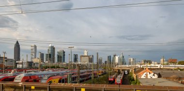 Trenler yan tarafa park ediyor. Frankfurt Almanya - 19 Temmuz 2023: Sinyal sistemleri, demiryolu bağlantıları ve şalterleri. Arkaplanda binalar, gökdelenler.