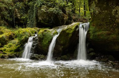 Mullerthal, Lüksemburg tepelerinde Schiessentempel şelalesi. Kara Ernz nehri vadiden akar. Yaz, yeşil yosun, orman.