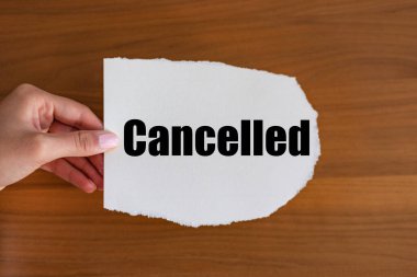 İptal edildi. Kadın eli, elinde bir notla bir kağıt parçası tutuyor ve iptal oluyor. Durduruldu, uyarı, bilgi, duyuru, iptal edilen olay veya uçuş.