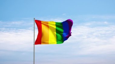 Bulutlu gökyüzüne karşı LGBTQ bayrağı. Rüzgarda sallanan LGBTQ bayrağı, hareket sembolü. Topluluk, bayrak, çeşitlilik, cinsiyet kültürü, özgür, bağımsız, aktivist.