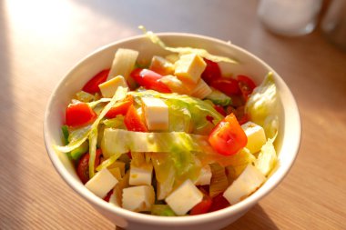 Mutfak masasındaki kasede sebze salatası yakın plan. Domates, peynir, hindiba, soğan, sos ve zeytinyağı. Sağlıklı yemek, lezzetli salata, çiğ sebze..