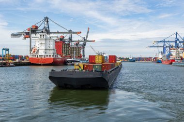 Hollanda Rotterdam Temmuz 2024 - Rotterdam yük ve sanayi limanında kargo terminali. Konteynırlarla dolu bir gemi, geçişi bekliyor..