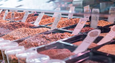 Ceviz, badem, macadamia, ceviz, kaju, fındık gibi farklı tohum ve fındık çeşitleri. Rotterdam 'daki pazar yerinde. Çiğ, yiyecek, malzeme, badem, ayçekirdeği, piyasa simsarı, fiyat etiketleri.