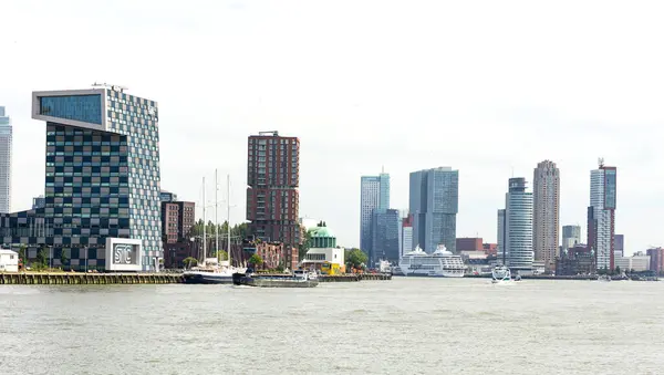 stock image Rotterdam Netherlands - July 9, 2024: Cityscape and modern architecture of Rotterdam. View from the seaward side of the Nieuwe Maas. A passenger ship for tourists is moored at the cruise terminal.