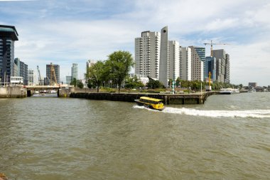 Rotterdam Hollanda - 9 Temmuz 2024: Rotterdam şehrinin bir parçası, bir su aracı Leuvehaven 'a doğru ilerliyor. Ofis ve konut binaları arka planda.
