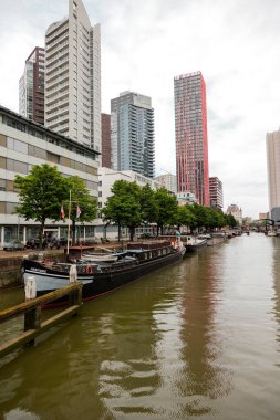 Rotterdam Hollanda - 9 Temmuz 2024: Rotterdam 'daki Sheepmakers Limanı manzarası. Küçük tekneler, büyük nakliye gemileri, ofis ve soldaki konut binaları..