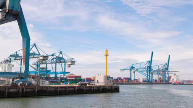 Rotterdam Hollanda - 9 Temmuz 2024: Kargo vinçleri, konteynır ve nakliye gemileriyle Rotterdam limanının görüntüsü yazın hafif bulutlu bir günde. Uluslararası yük ve mal taşımacılığı.