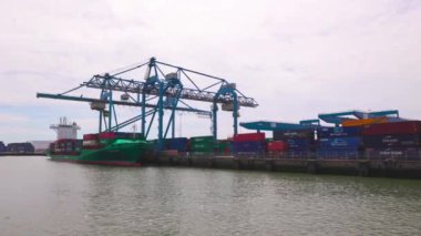 Rotterdam Hollanda - 9 Temmuz 2024: Rotterdam Limanı, kargo vinciyle doldurulan yeşil bir nakliye gemisi, yazın bulutlu bir gün. Uluslararası yük ve mal taşımacılığı.