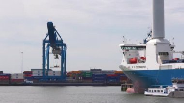 Rotterdam Hollanda - 9 Temmuz 2024: Rotterdam Limanı, sağ tarafta mavi bir kargo gemisi. Vinçler ve konteynırlar arka planda. Uluslararası yük ve mal taşımacılığı.