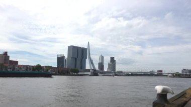 Rotterdam Hollanda - 9 Temmuz 2024: Güneşli bir günde Erasmus Köprüsü ve De Rotterdam binasının manzarası. Bir nakliye gemisi geçiyor..