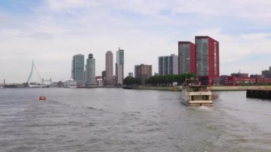 Rotterdam Hollanda - 9 Temmuz 2024: Erasmus Köprüsü ve gemi terminali ile kentin manzarası. Ön planda turistlerle dolu bir gezi teknesi var..