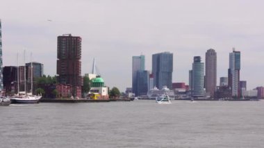 Rotterdam Hollanda - 9 Temmuz 2024: Arka planda Erasmus Köprüsü manzaralı tekne manzaralı şehir manzarası, bazı ofis ve konut binaları ve limana demirlemiş bir yolcu gemisi.