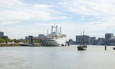 Rotterdam, Hollanda - 9 Temmuz 2004: Arkadan eski yolcu gemisi Rotterdam 'ın görüntüsü. Yelken direkli eski bir yelkenli gemi geçiyor..