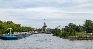 Rotterdam, Hollanda - 9 Temmuz 2004: Rıhtımda nakliye gemileri ve arka planda bir yel değirmeni olan bir liman koyuna bakın.