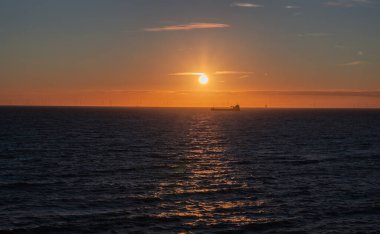 Transport ship and wind farm in the North Sea, sunset at Scheveningen, The Hague, Netherlands. NAtur, warm light, panorama, tranquil scene, clear sky. clipart