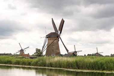 Tarihi yel değirmenleri grubu su kenarına yakın. Hollanda 'daki Kinderdijk, bulutlu bir gün, yaz.