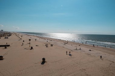 Lahey, Hollanda - 10 Temmuz 2024: Günbatımında Scheveningen 'de halk plajında insanlar. Açık gökyüzü ve sakin deniz.