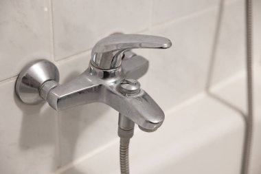 Küvetin üstündeki eski kireçlenmiş banyo. Beyaz desenli kiremitleri olan duvar. 