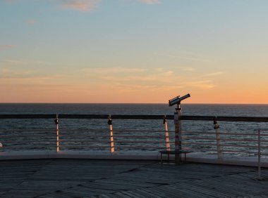 Scheveningen 'deki iskelenin kenarındaki dürbünler. Gün batımı, sıcak ışık, sakin sahne. Lahey, Hollanda.