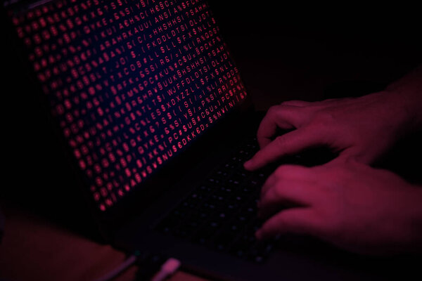 Руки печатают на клавиатуре компьютера, красный свет, киберпреступления. Технология, кибератака, взлом системы, вирус, бинарный код.