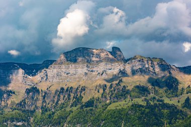 Ağaçlı dağ zirvesi, İsviçre, Canton St. Gallen, İsviçre Alpleri, Fruemsel ve Hinterrugg dağları. Güneşli bir gün, bulutlar, sıradağlar. Yürüyüş, turizm, seyahat yeri, dinlenme yeri.