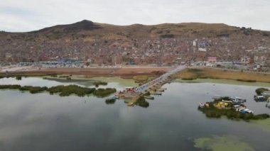 Sabah Peru, Puno 'daki Titicaca Gölü' ndeki rıhtımda 4K Hava Arc yörüngesi. Şehir, kayıklar ve görünen dağlar..