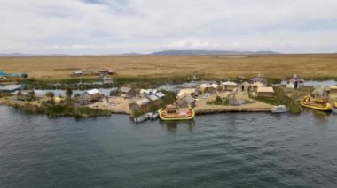 Peru, Puno yakınlarındaki Titicaca Gölü 'ndeki Uros Adaları etrafında 4K Hava Arc. Otantik tekne, göl, sazlıklar ve görünür yüzen adalar..