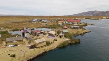 Peru, Puno yakınlarındaki Titicaca Gölü 'ndeki Uros Adaları etrafında 4K Hava Arc. Otantik tekne, göl, sazlıklar ve görünür yüzen adalar..