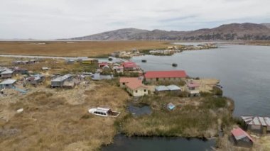4K Hava Aracı Uros Adaları 'nı ve Titicaca Gölü, Puno, Peru' da sazlık taşıyan tekneleri görüyor. Otantik Tekne, Göl, Sazlıklar, Yüzen Adalar görünür.