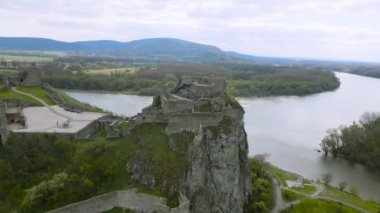 4K Hava Aracı nehir kıvrımındaki antik kalenin yörüngesinde dönüyor. Slovakya, Bratislava yakınlarındaki Devin Kalesi