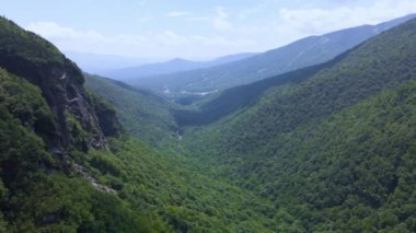 Güneşli bir günde 4K Hava Aracı Orman Dağı Vadisi 'nden uçar. Bulutlar ve gölgeler görünür