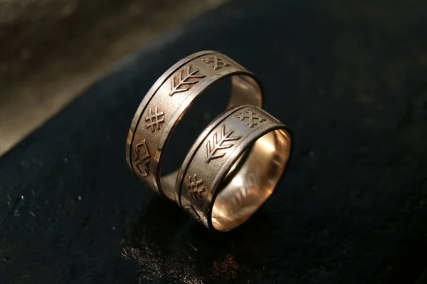Two gold rings. Gold wedding rings with ancient symbols.