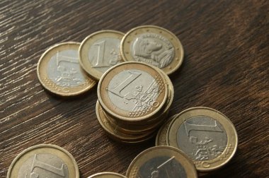 Avrupa paraları. Koyu ahşap bir masada 1 euro sikke.