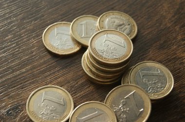 Koyu ahşap bir masada 1 euro sikke. Bimetalik Avrupa paraları.