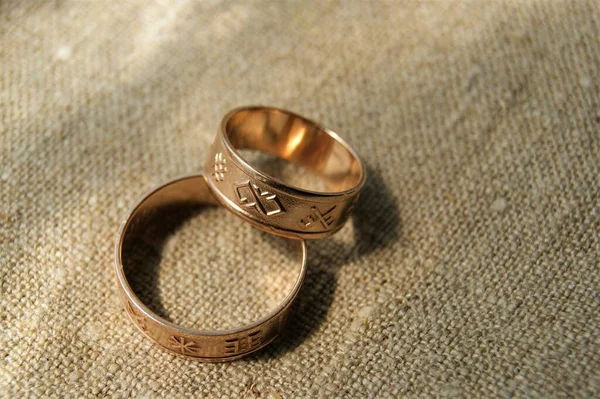 Gold wedding rings with ancient symbols. Rings on linen fabric. Latvian ancient symbols.