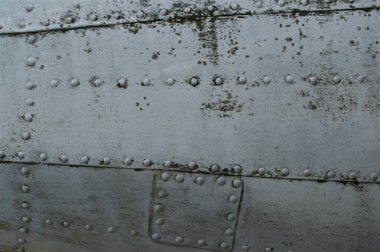 Eski bir uçağın perçinlenmiş gövdesi. Antika metalik arkaplan.