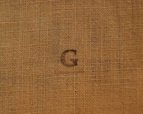 Keten kumaş üzerindeki G harfi.