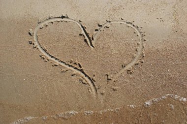 Islak kuma çizilmiş bir kalp. Aşk ve duygular.