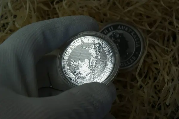 Silver coin in capsule in numismatist\'s hand. United Kingdom silver coin 2 pounds Britania 2023. Pure silver Investment coin.