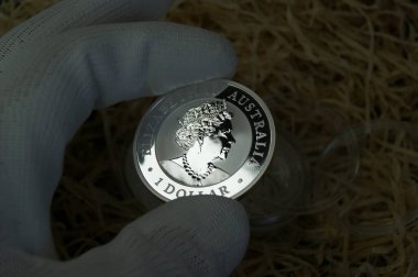 Değer biçen birinin elinde gümüş bir para. Avustralya saf gümüş yatırım parası. 2. Elizabeth 1 dolar.,
