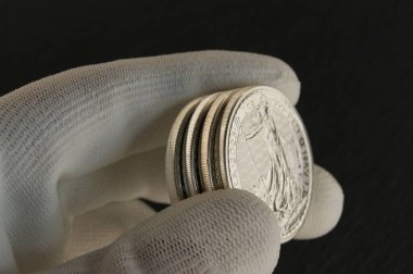 Nümismatistin elinde gümüş paralar. Bozuk paraların kenarları. 1 kilo Britanya.