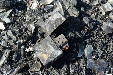 Yangının sonuçları. Kül içinde yanmış metal çakmak. Yakın plan..