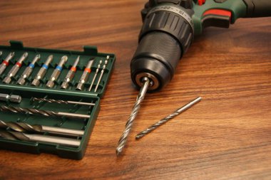 Yeni matkap seti. Bir matkap ve bir takım matkaplar karanlık bir tahta masa üzerinde.