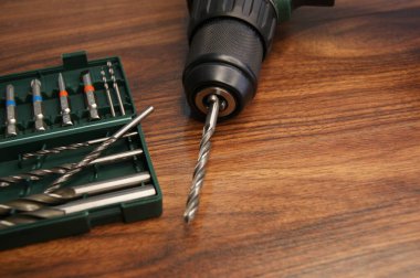 Koyu ahşap bir masada matkap ve matkap seti. Yakın plan.