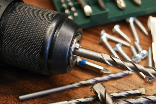 Ahşap arka planda matkaplar ve çeşitli malzemelerle hazırlanmış bir matkabın yakın plan çekimi..