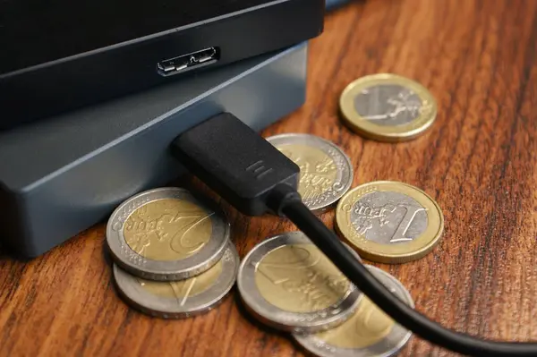 External hard drives and euro coins.. External hard drive with cable close-up.
