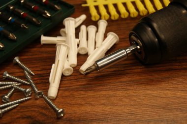 Montajcının çalışma süreci. Koyu ahşap bir yüzeyde vidalar, plastik kaplamalar ve tornavidalar..